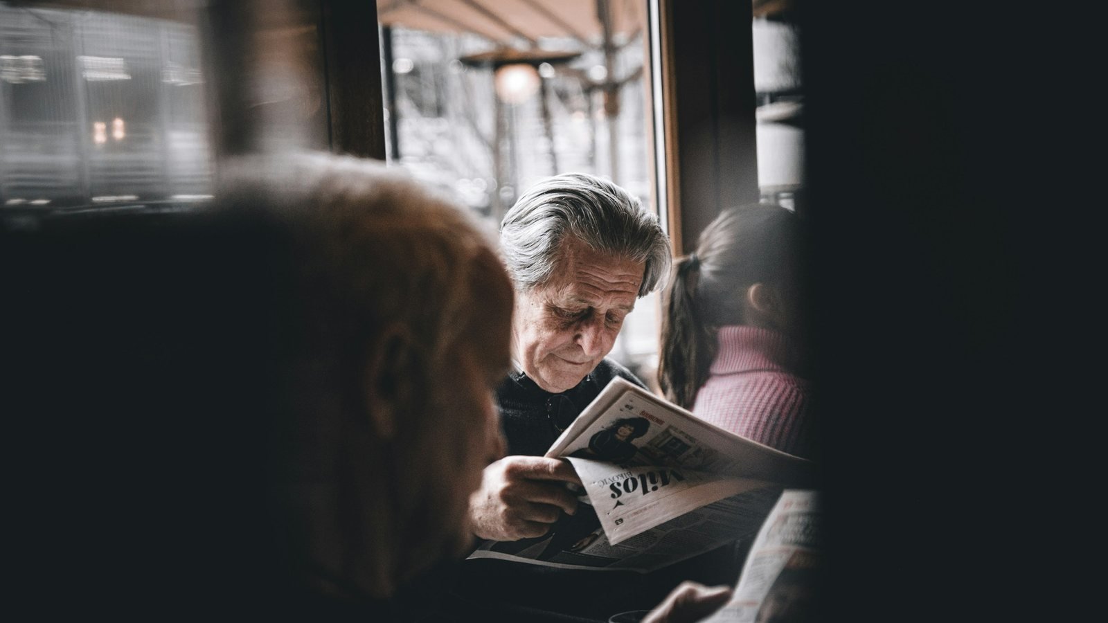 Homme âgé lisant un journal dans un café