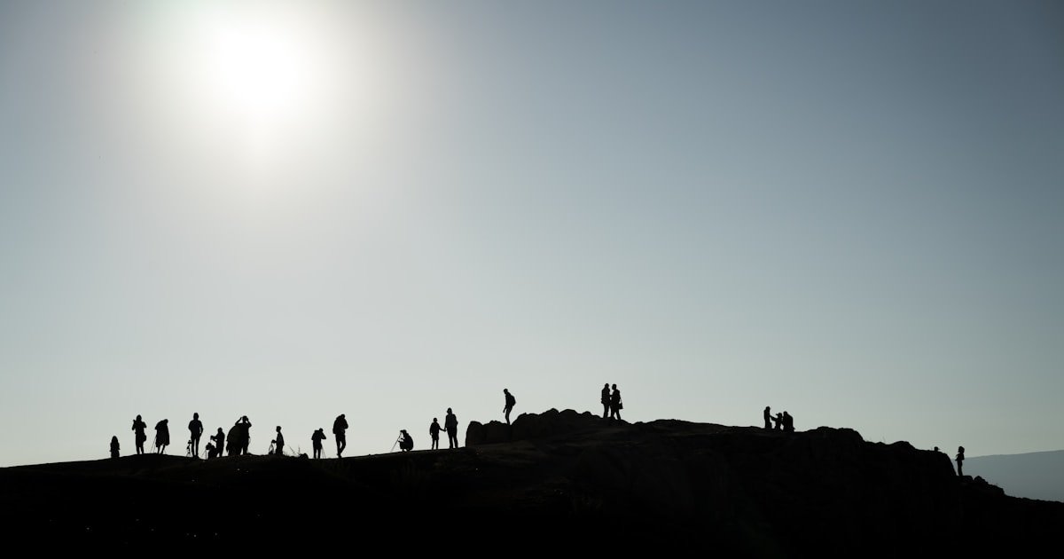 Grupo de pessoas reunidas numa crista para observar o Sol