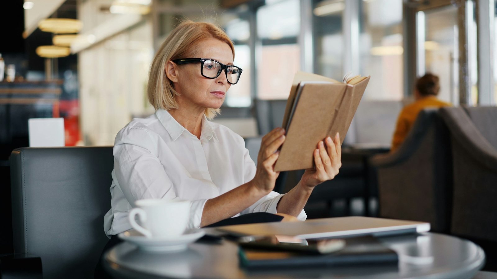 Femme d’une cinquantaine d’années lisant un livre tenu à bout de bras