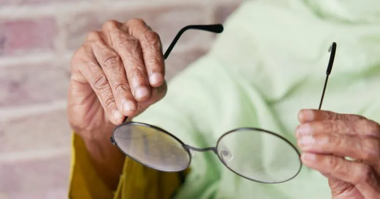 Femme âgée tenant ses lunettes, récupération après chirurgie de la cataracte