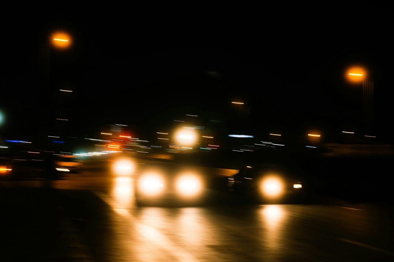 Phares de voitures flous et halos lumineux sur une route de nuit
