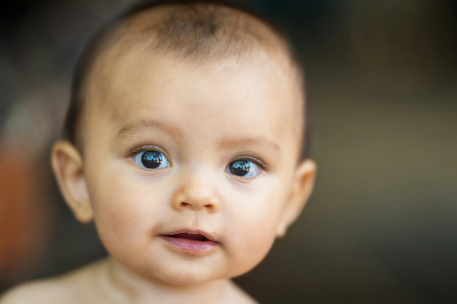 Close-up of a baby's face with wide-open eyes staring at the camera