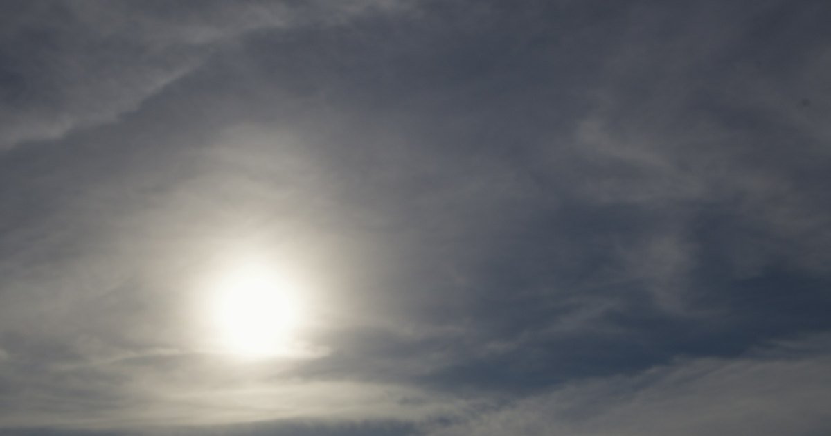 Sol velado por trás de uma fina camada de nuvens, num céu cinzento
