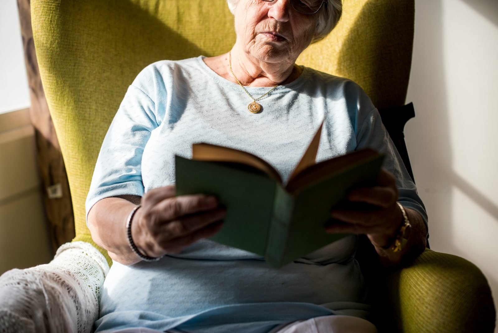Femme âgée lisant un livre dans un fauteuil