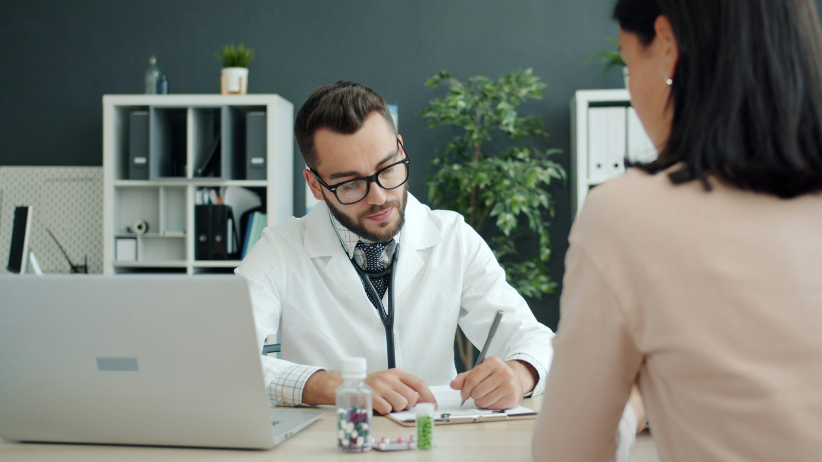 Médecin prenant des notes face à une patiente en consultation