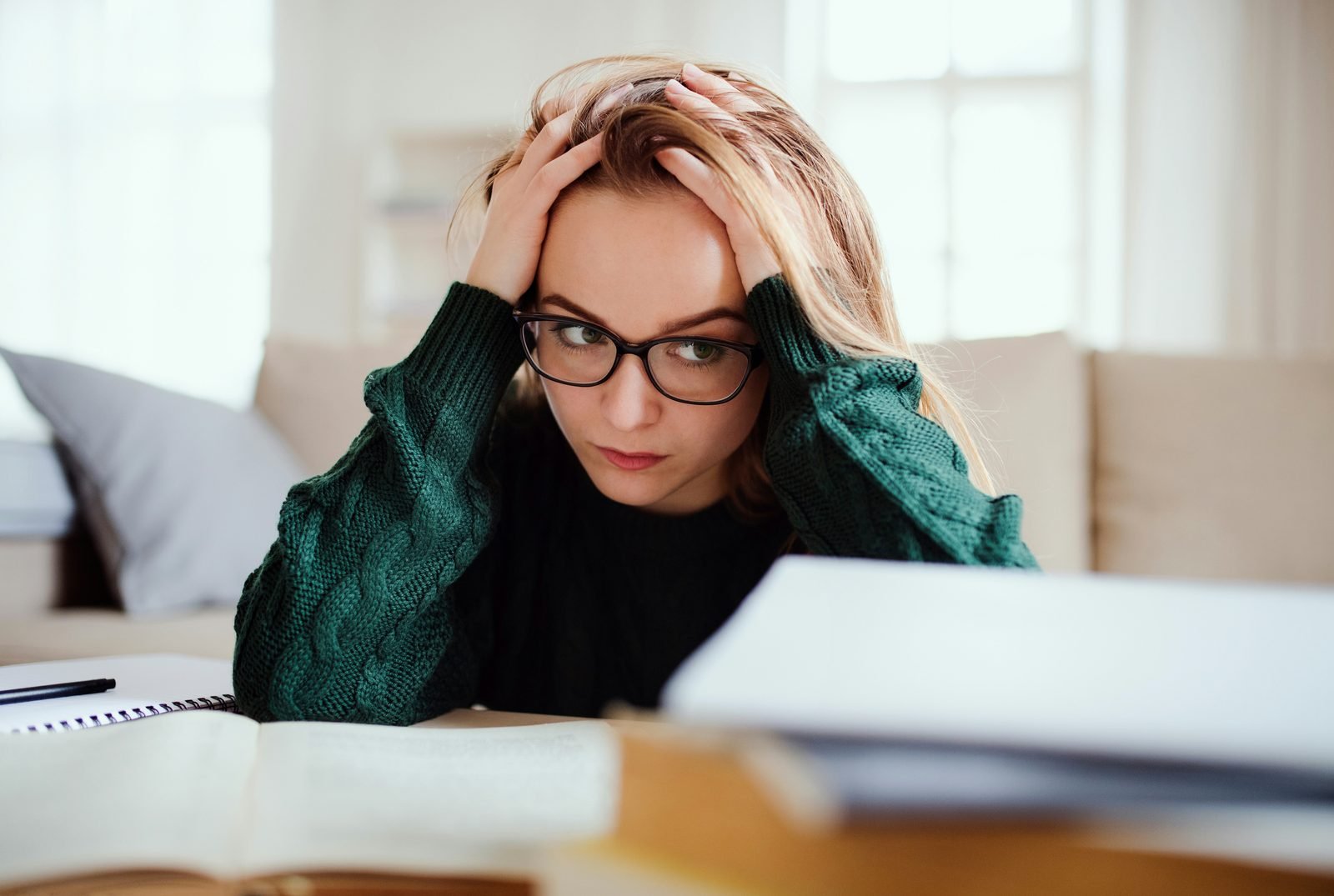 Jeune femme fatiguée devant des documents, les mains sur la tête