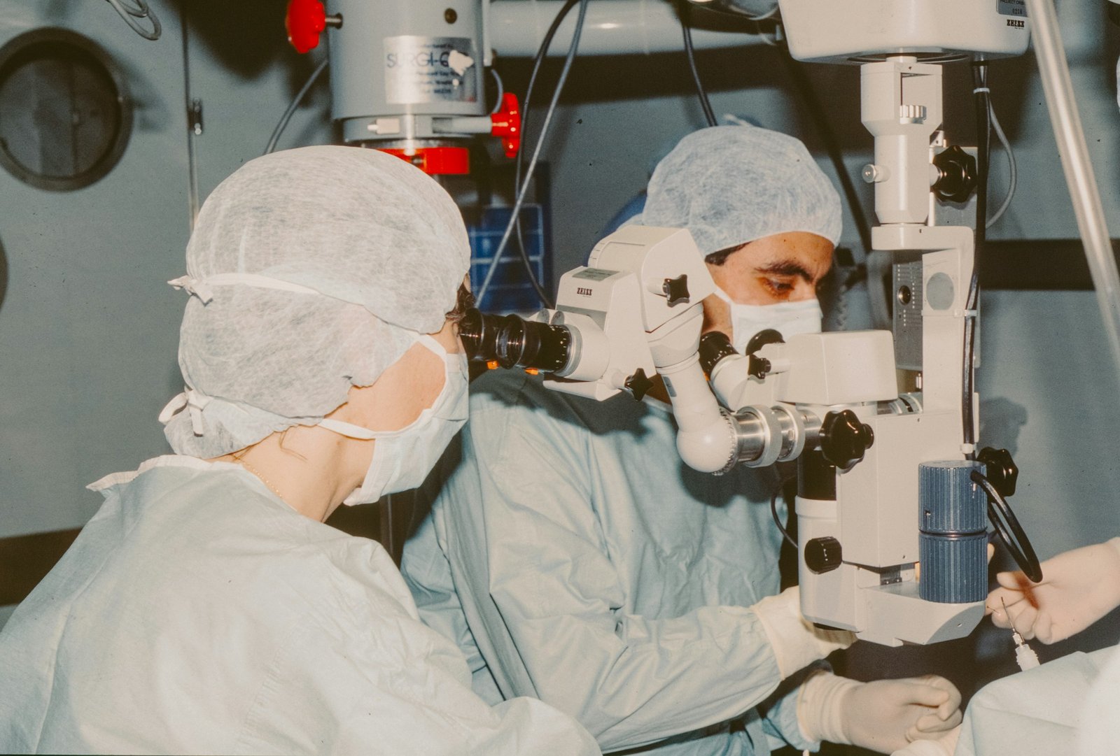 Équipe chirurgicale travaillant au microscope opératoire en environnement stérile