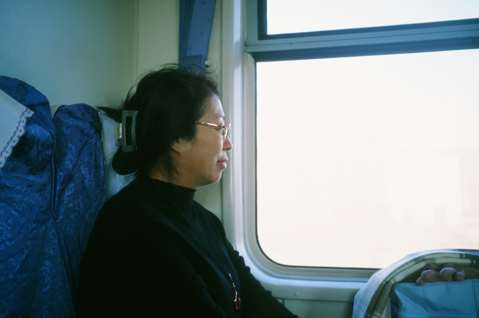 Jeune femme portant des lunettes, regardant le paysage par la fenêtre d'un train