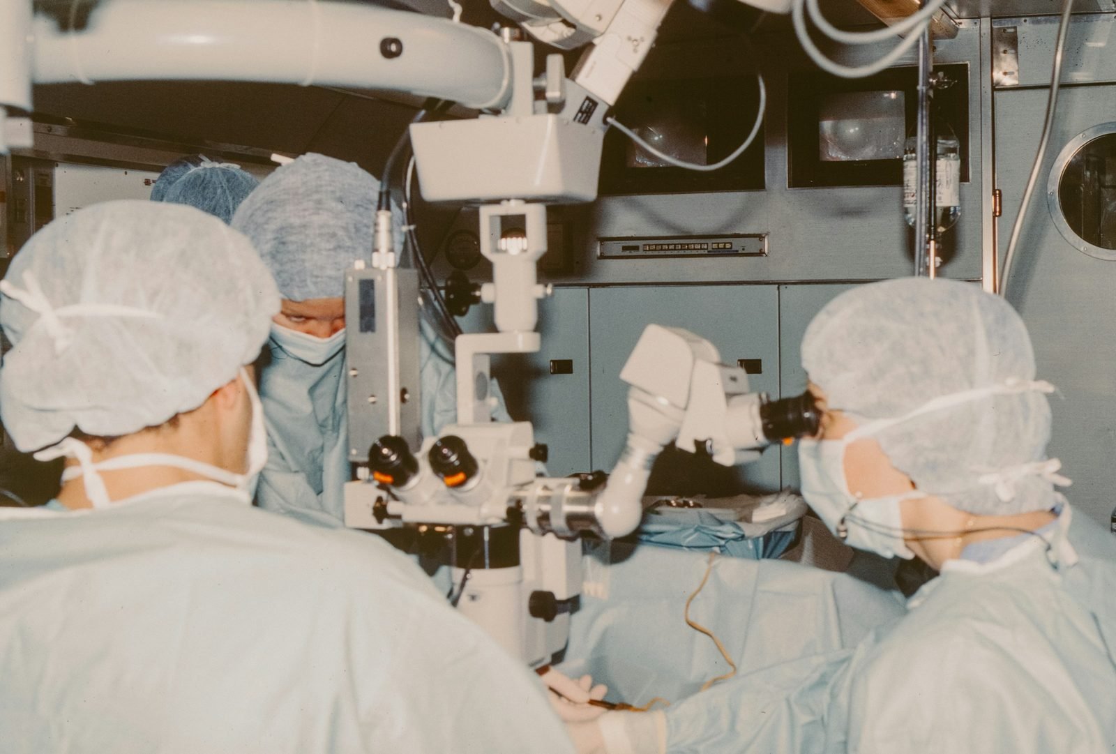 Équipe chirurgicale au microscope opératoire pendant une intervention ophtalmologique