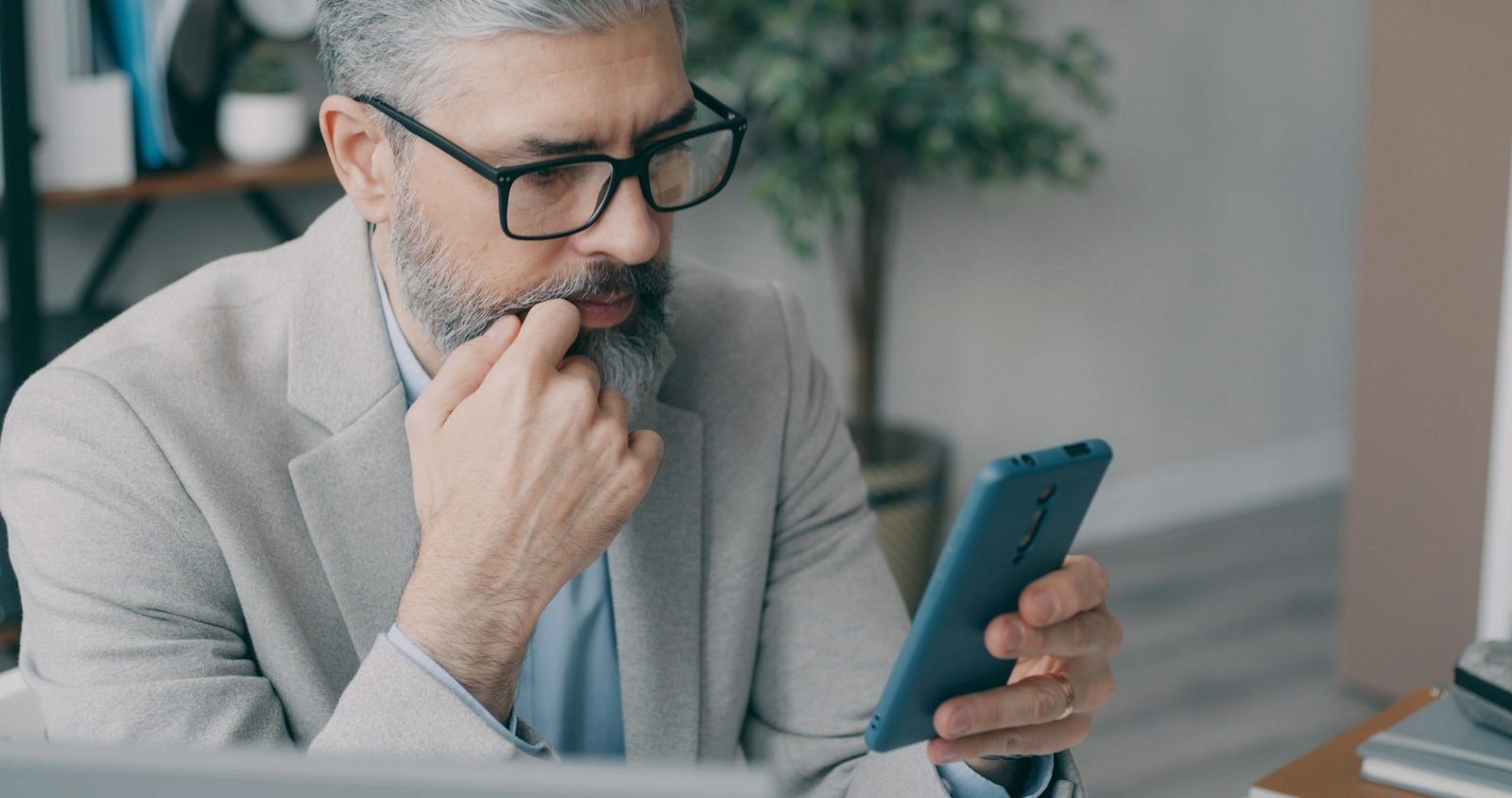 Homme d'une cinquantaine d'années éloignant son téléphone pour lire l'écran