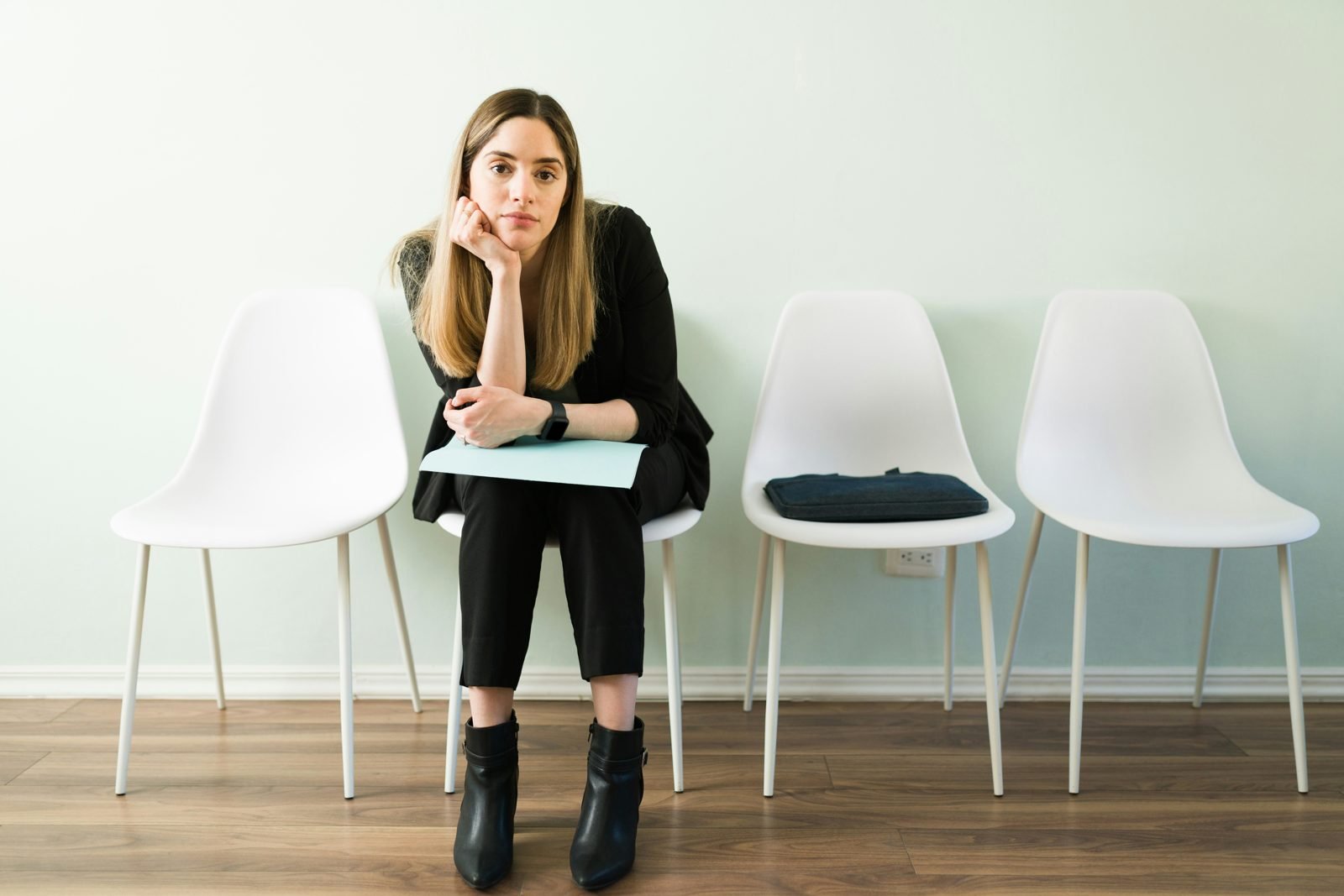 Donna seduta in una sala d’attesa, con il mento appoggiato sulla mano