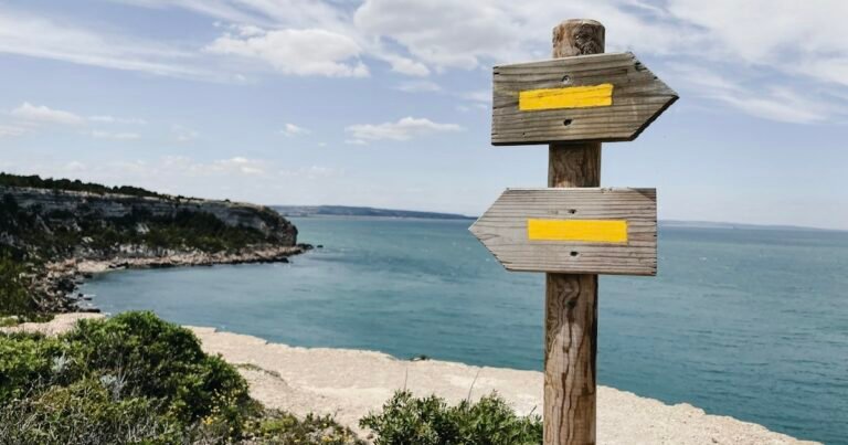 Wooden signpost pointing in two directions by the sea