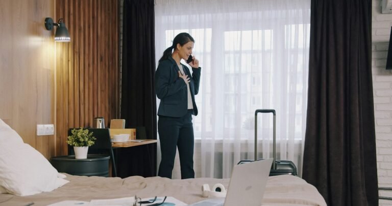 Woman on the phone, standing by a window in a bedroom