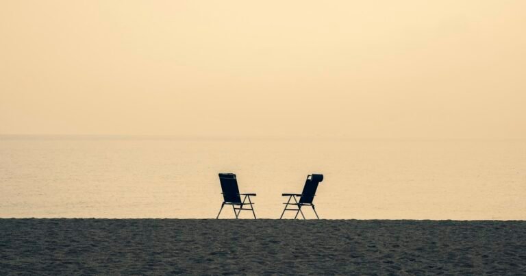 Two chairs facing each other on a beach at dusk