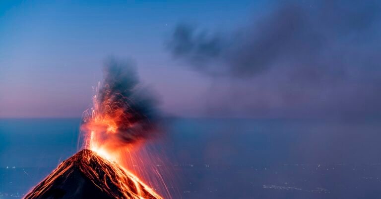 Volcano erupting at dusk, with glowing lava flowing down