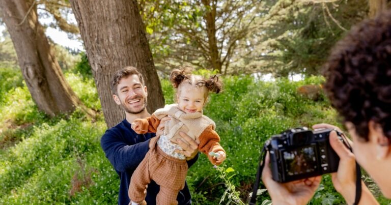 A father holds his little daughter while they are photographed in a park