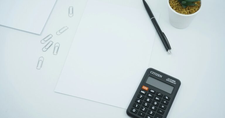 Calculator, pen and blank sheets on a desk