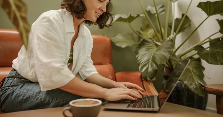 Smiling woman working on a laptop, surrounded by plants