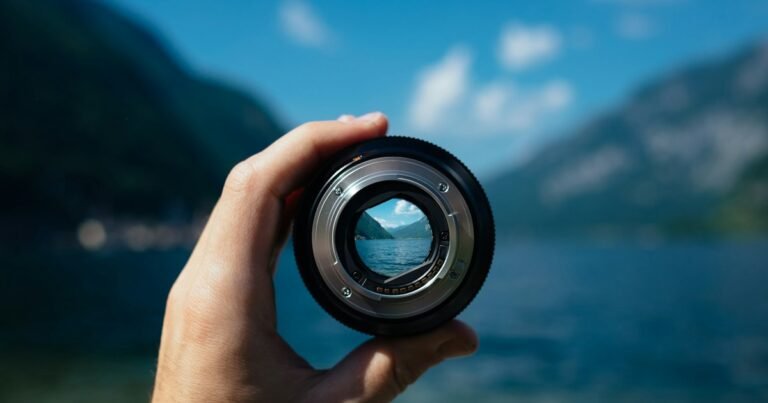 Camera lens held up to a mountain lake, the landscape sharp inside it